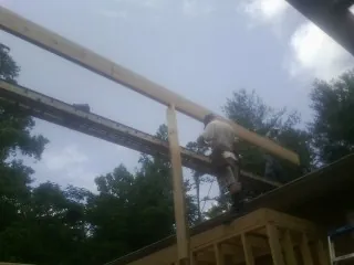 Carpenter setting a ridge beam over a new addition frame — Ice Dam Removal by Roofing Brothers in Gentry
