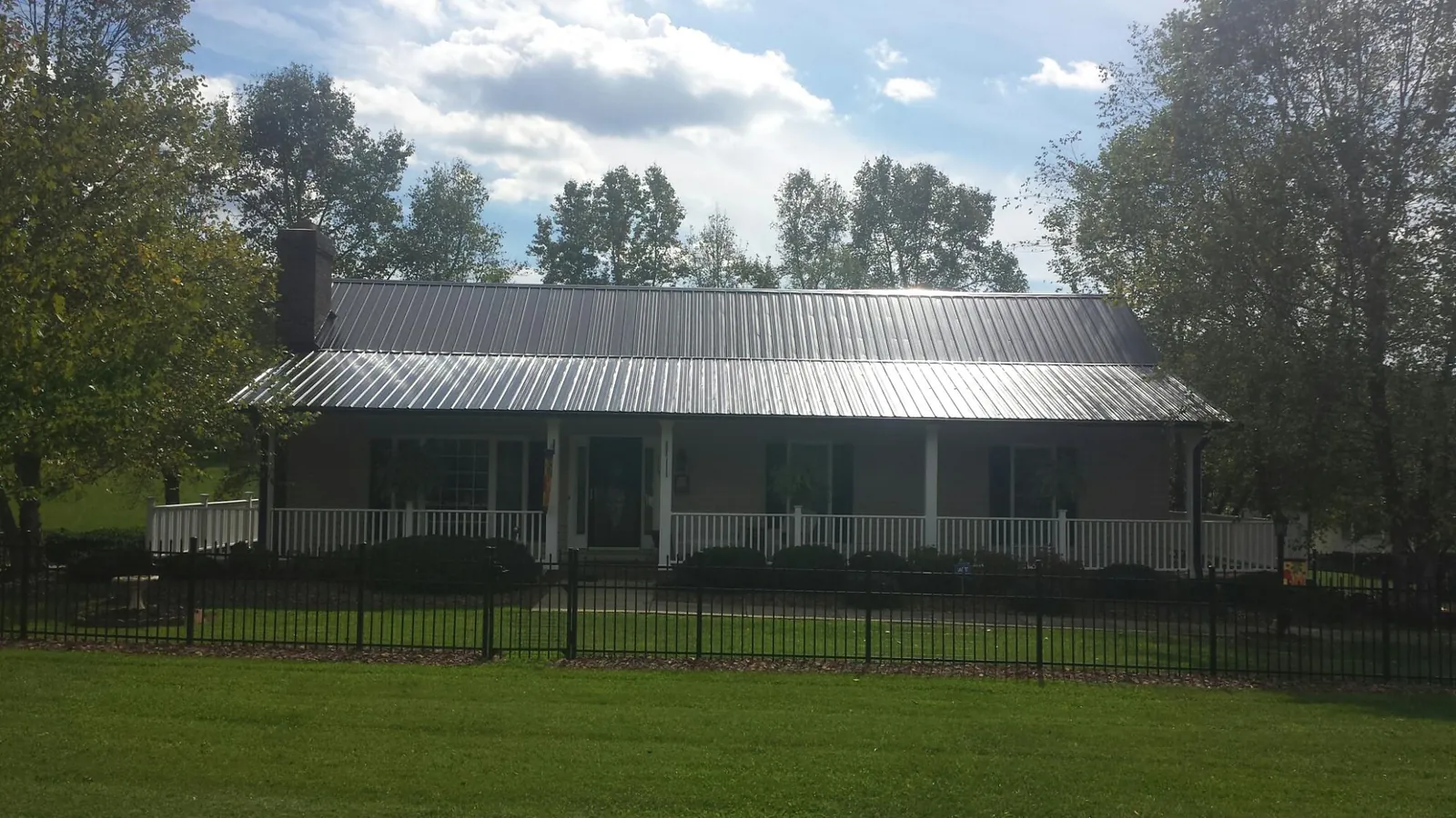 Gray metal roof on a brick ranch with a full width front porch — Gutter Guard Installation work by our crew in Gentry