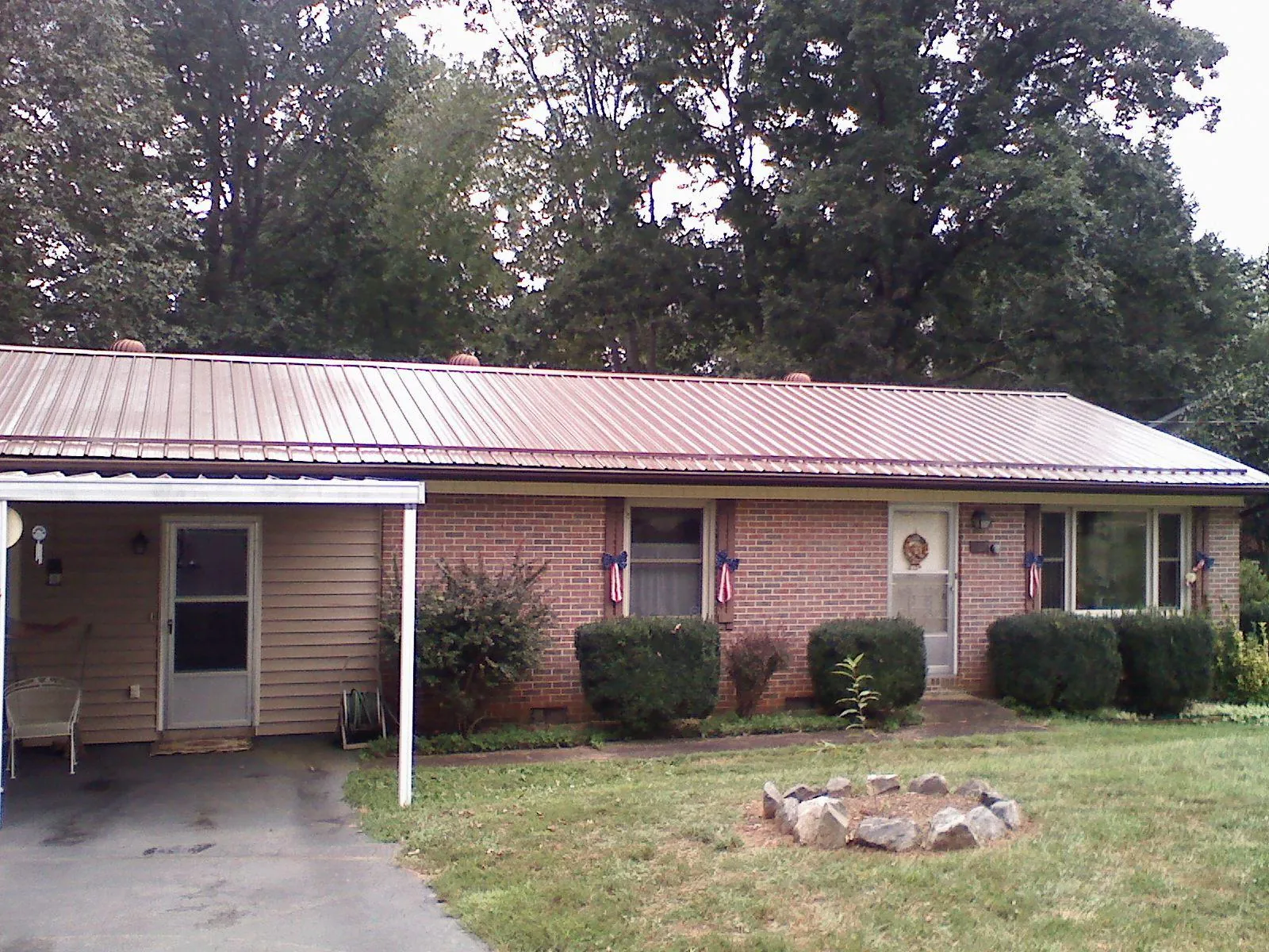 Bronze metal roof and carport on a brick ranch home — Roof Repair work by our crew in Gentry